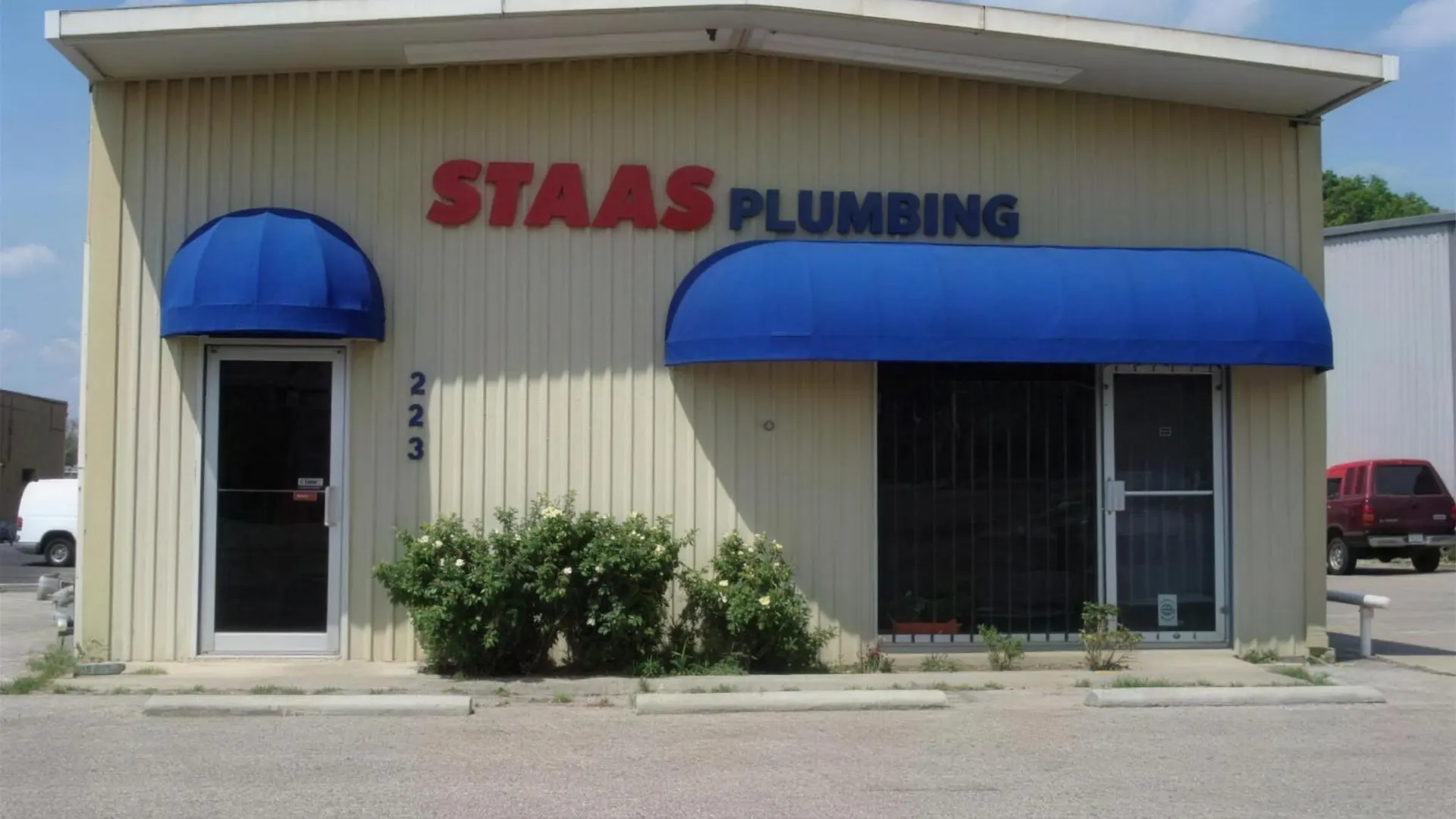 Staas Plumbing storefront with a blue awning and a red and blue sign